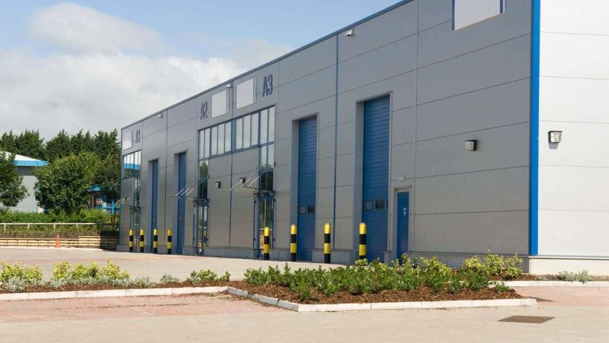 Gewerbegebäude mit mehreren Rolltoren und blauen Akzenten an der Fassade.