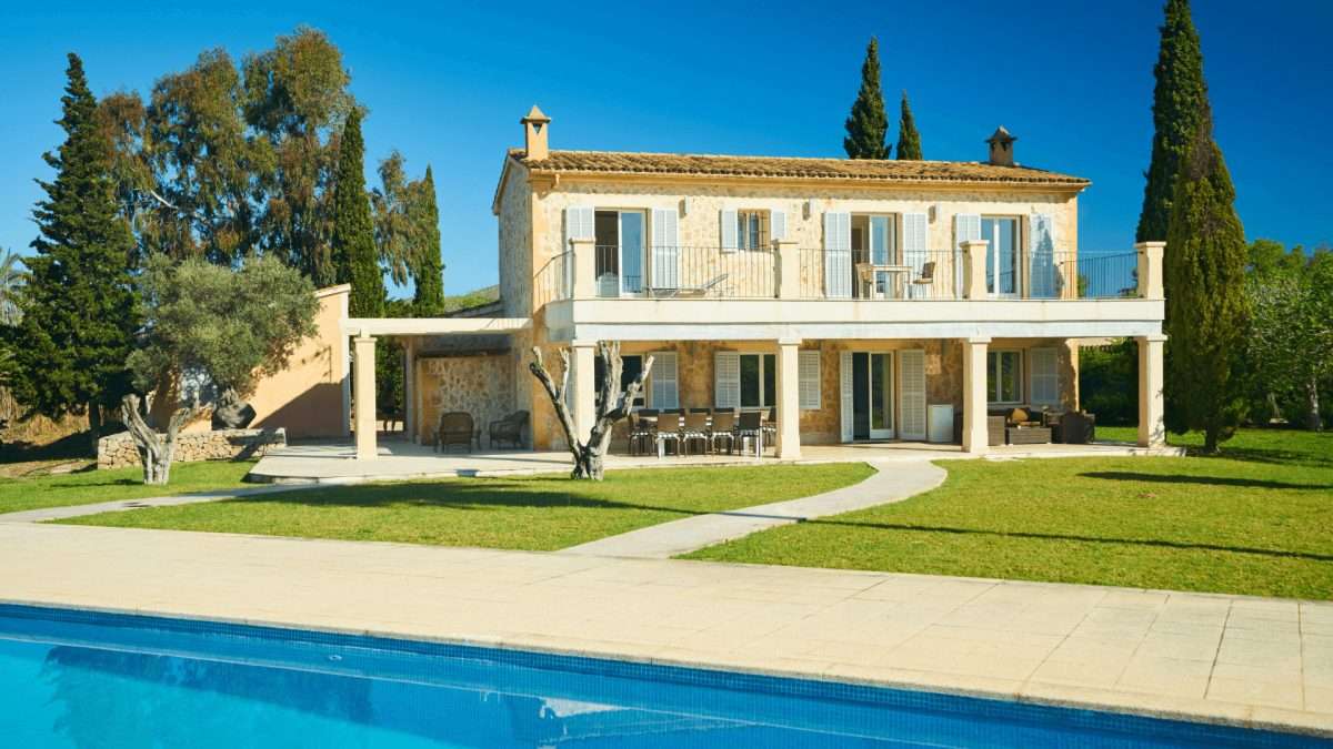 Zweistöckiges Ferienhaus mit Balkon, Garten und Swimmingpool in sonniger Umgebung.