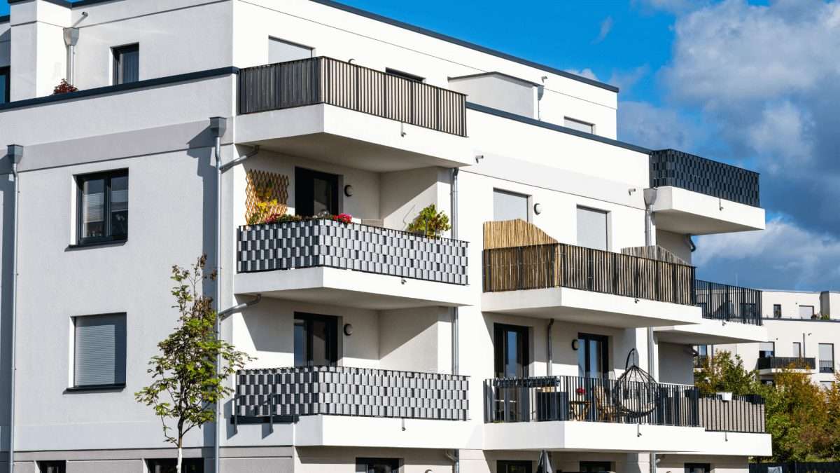 Modernes Mehrfamilienhaus mit weißen Wänden und mehreren Balkonen in unterschiedlichen Designs.